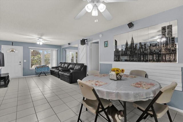 dining space with light tile patterned flooring, a ceiling fan, baseboards, and a textured ceiling