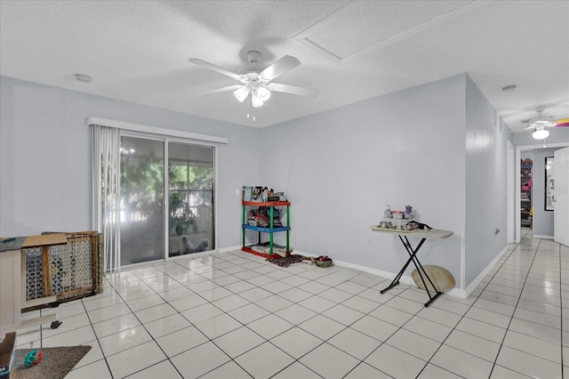 interior space featuring light tile patterned floors, a textured ceiling, baseboards, and ceiling fan