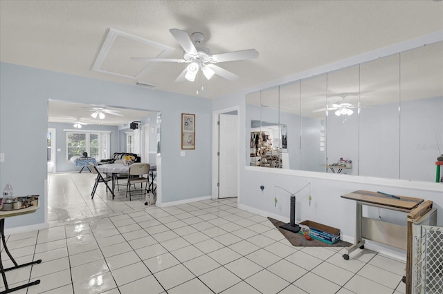 interior space with visible vents, light tile patterned floors, a ceiling fan, and baseboards