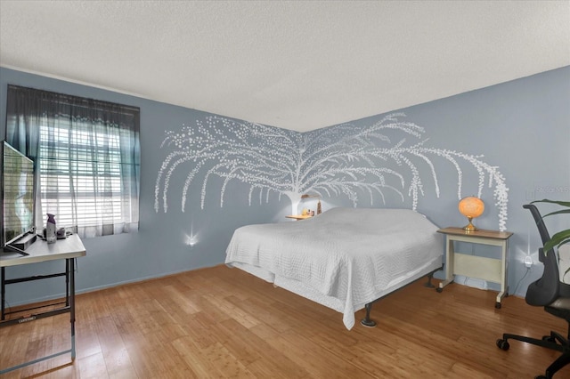 bedroom featuring a textured ceiling, baseboards, and wood finished floors