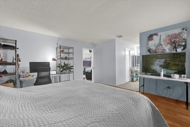 bedroom featuring visible vents, a textured ceiling, and wood finished floors