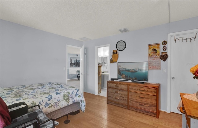 bedroom with wood finished floors, visible vents, and a textured ceiling