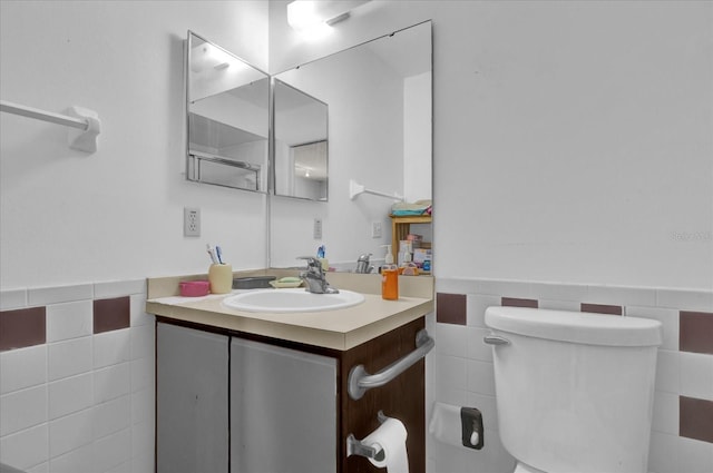 bathroom featuring vanity, tile walls, toilet, and a wainscoted wall