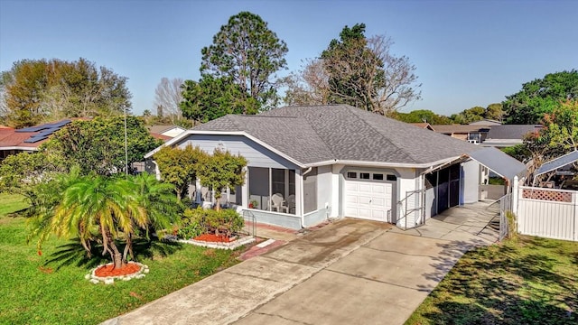 view of front of house featuring driveway, roof with shingles, a front yard, a sunroom, and a garage