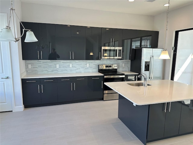 kitchen featuring dark cabinetry, a sink, light countertops, appliances with stainless steel finishes, and tasteful backsplash