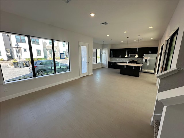 kitchen with visible vents, open floor plan, dark cabinetry, stainless steel appliances, and light countertops