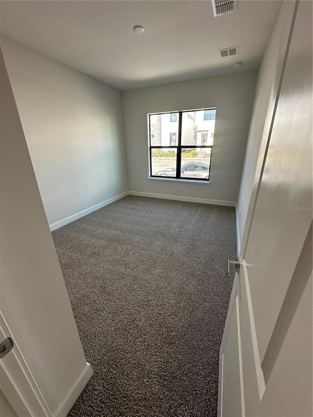 spare room featuring carpet, visible vents, and baseboards