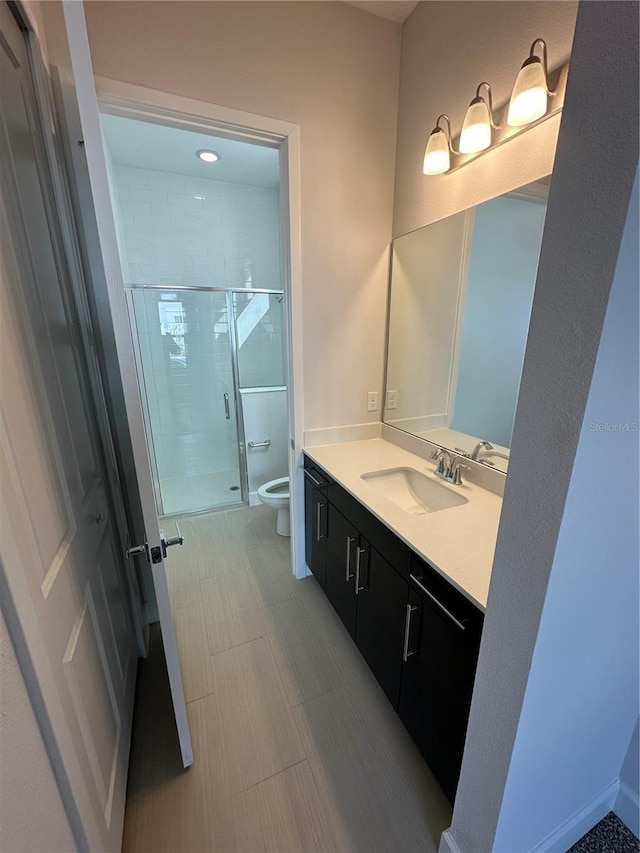 bathroom featuring a shower stall, toilet, and vanity