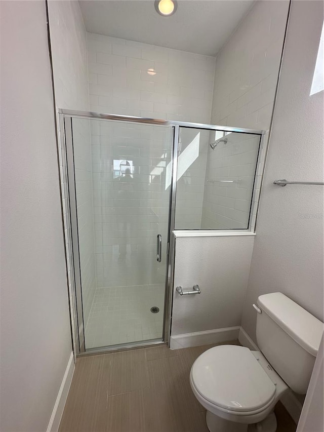 full bathroom with toilet, baseboards, and a stall shower