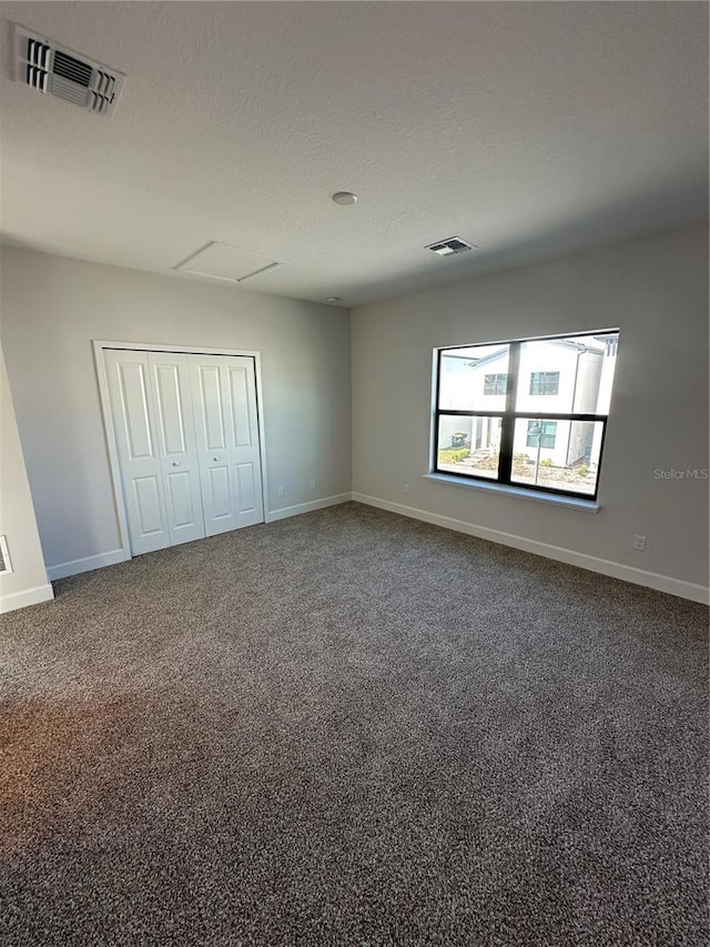 carpeted spare room featuring visible vents, baseboards, and a textured ceiling