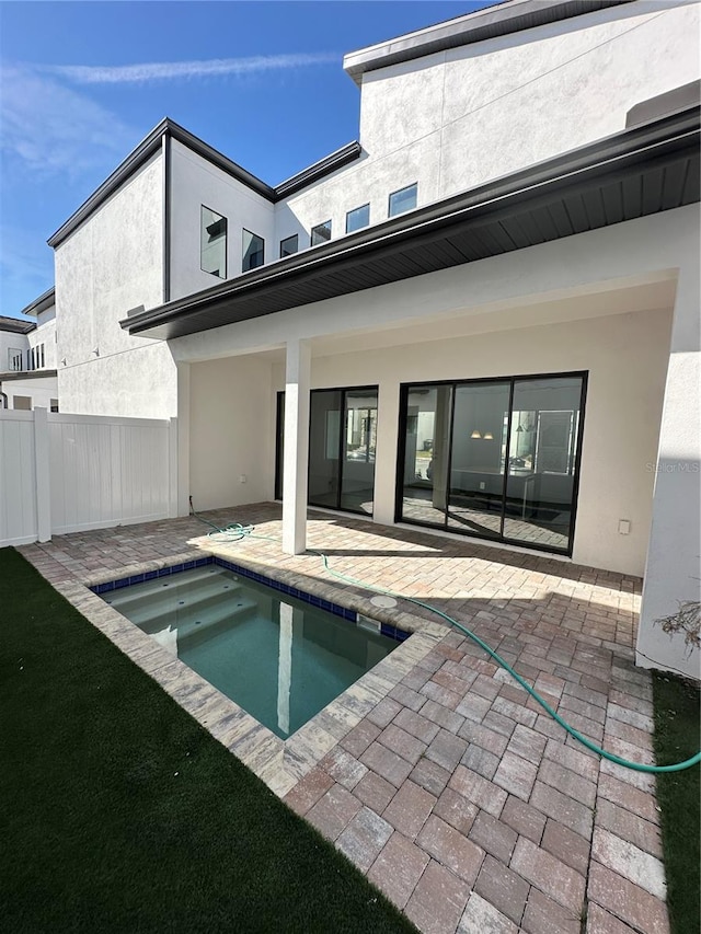 back of property with stucco siding, a patio, and fence