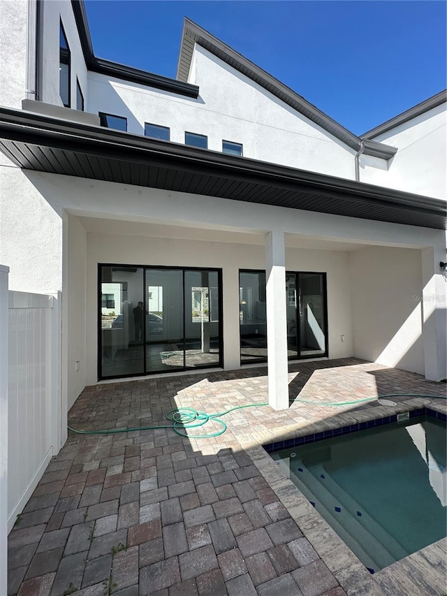 back of property featuring an outdoor pool, stucco siding, and a patio area