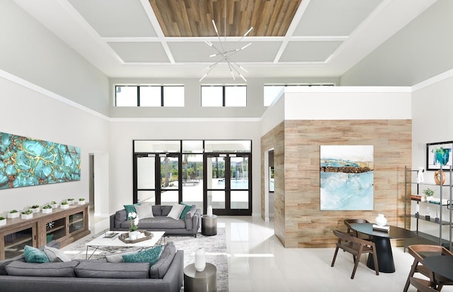 tiled living area featuring wooden walls, an accent wall, a chandelier, french doors, and a high ceiling