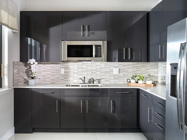 kitchen featuring modern cabinets, a sink, appliances with stainless steel finishes, light countertops, and decorative backsplash