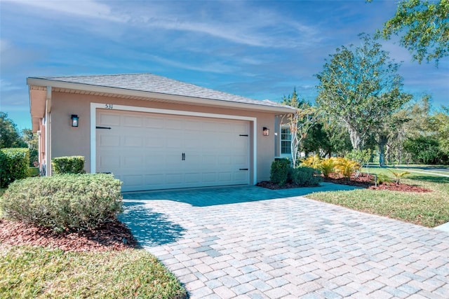 exterior space with stucco siding, a garage, and driveway