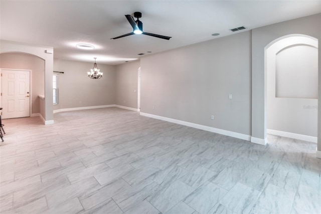 empty room with arched walkways, visible vents, ceiling fan with notable chandelier, and baseboards