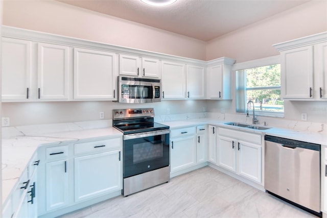 kitchen with a sink, light stone counters, white cabinetry, and stainless steel appliances