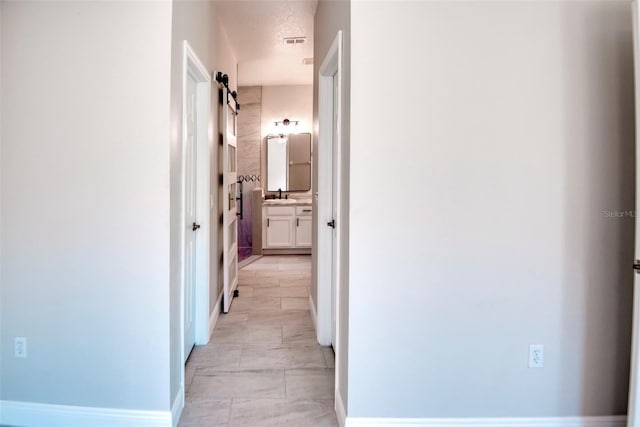 corridor with visible vents, baseboards, and a sink