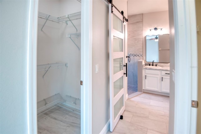 bathroom with a ceiling fan, a spacious closet, and vanity