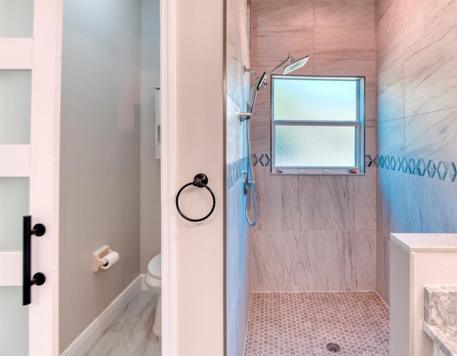 full bathroom featuring toilet, baseboards, and a tile shower