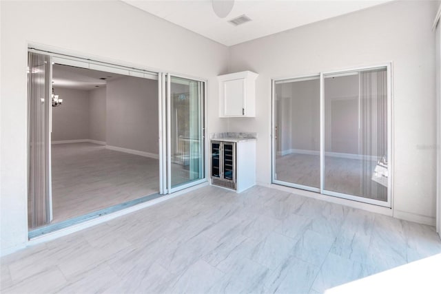 interior space featuring visible vents, baseboards, indoor bar, wine cooler, and an inviting chandelier