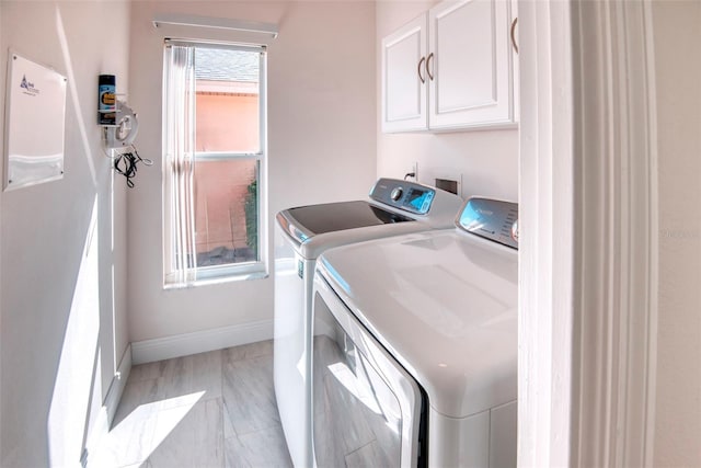 laundry room with cabinet space, washing machine and dryer, and baseboards