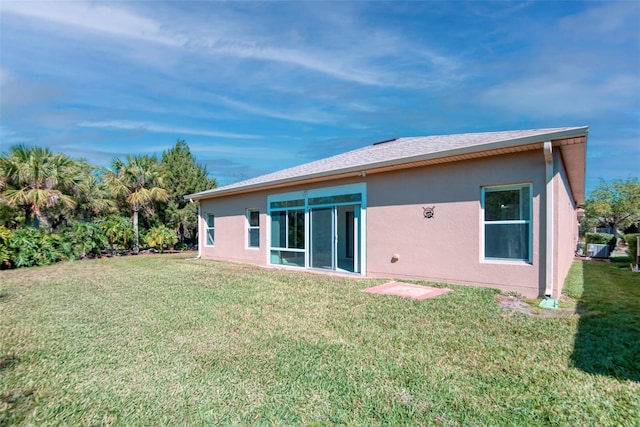 rear view of property featuring a yard and stucco siding