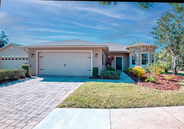 ranch-style house featuring a shingled roof, stucco siding, a front lawn, a garage, and decorative driveway