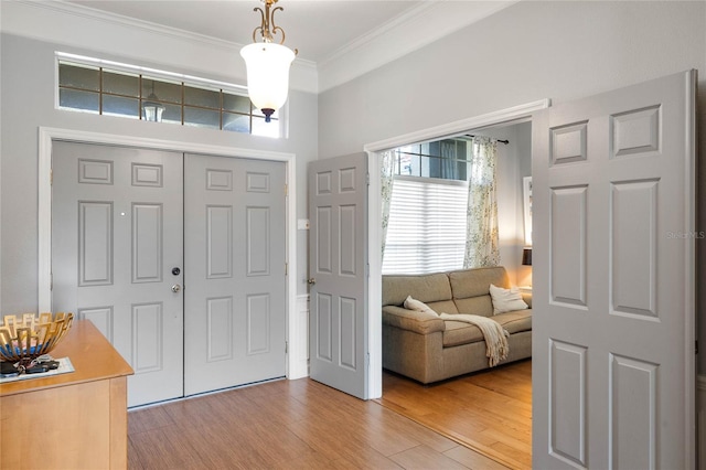 entryway with light wood-style flooring and ornamental molding