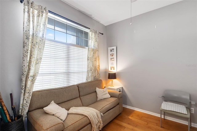 living area with baseboards and wood finished floors