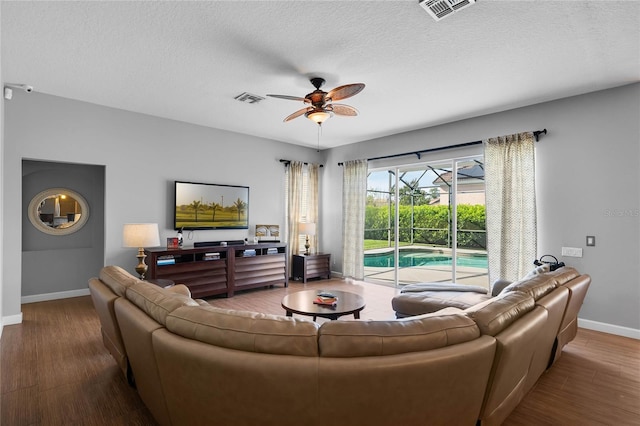 living room with wood finished floors, a ceiling fan, visible vents, and baseboards