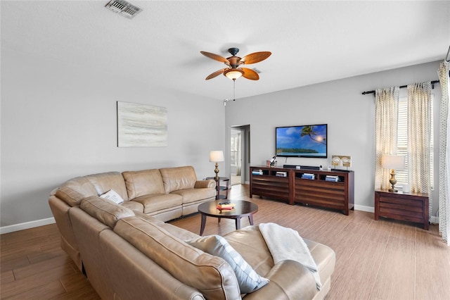 living room featuring visible vents, baseboards, light wood-style floors, and a ceiling fan