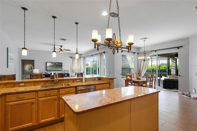 kitchen with visible vents, ceiling fan with notable chandelier, a sink, a center island, and dishwasher