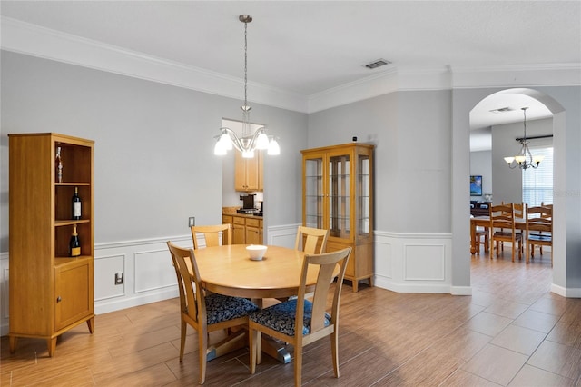 dining space with visible vents, wood finish floors, ornamental molding, arched walkways, and a notable chandelier