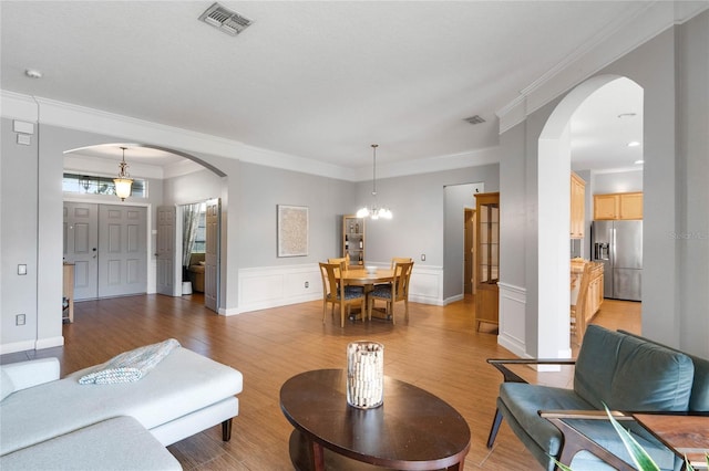 living room with visible vents, arched walkways, and light wood finished floors