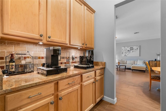 kitchen with visible vents, ornamental molding, light brown cabinetry, light stone counters, and tasteful backsplash