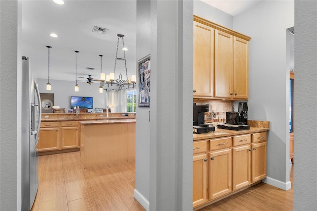 kitchen with light wood-style flooring, light brown cabinetry, decorative light fixtures, tasteful backsplash, and freestanding refrigerator