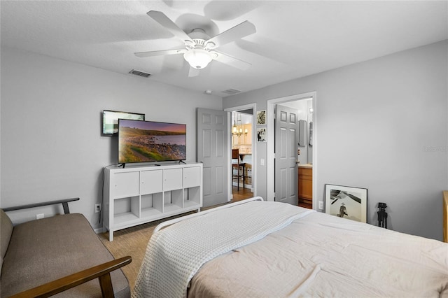 bedroom featuring visible vents, ensuite bathroom, a ceiling fan, and wood finished floors