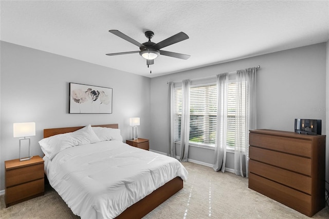 bedroom featuring light carpet, a textured ceiling, a ceiling fan, and baseboards