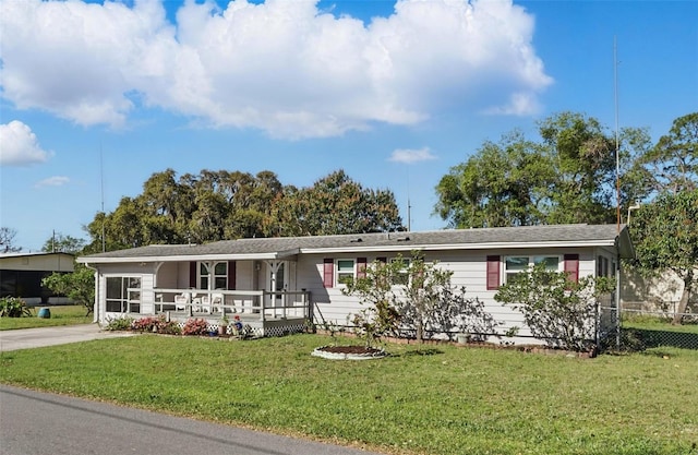 ranch-style house with a front yard, concrete driveway, fence, and covered porch