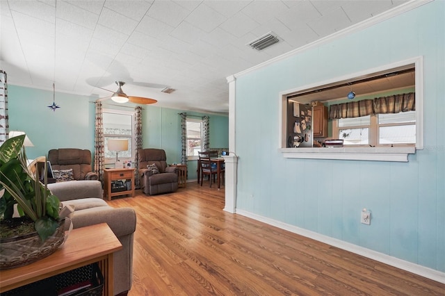 living area featuring visible vents, ornamental molding, ceiling fan, and wood finished floors