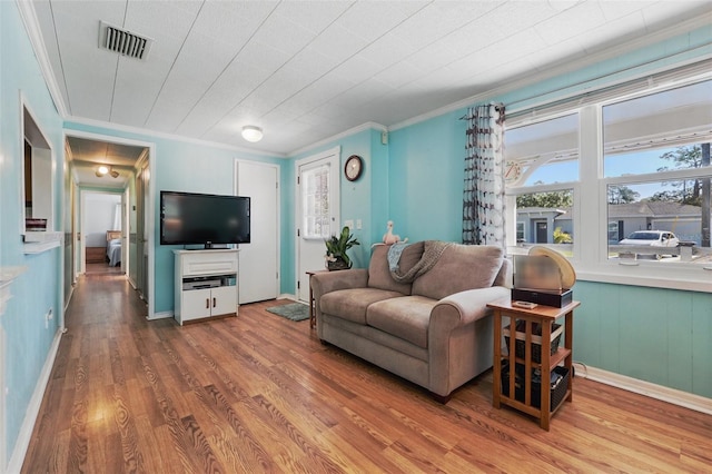 living area with visible vents, crown molding, and wood finished floors