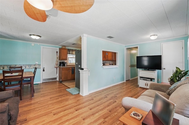 living area with visible vents, light wood-style flooring, and ornamental molding