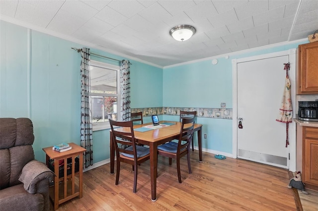 dining space with baseboards, light wood-style flooring, and crown molding