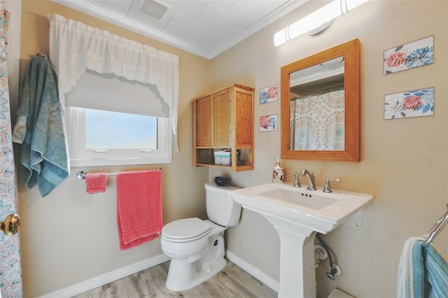 bathroom with visible vents, crown molding, baseboards, toilet, and wood finished floors