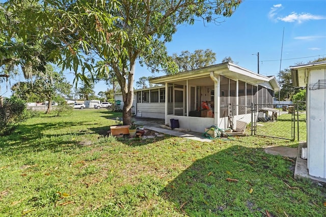 exterior space with a gate, a lawn, and a sunroom