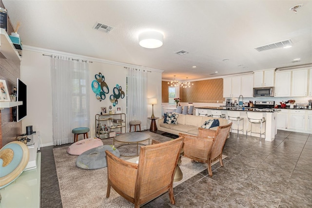 living area featuring visible vents, a chandelier, and crown molding