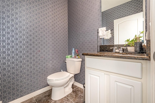 half bath featuring tile patterned flooring, toilet, vanity, and baseboards