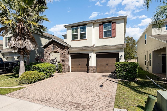 view of front of home with stucco siding, decorative driveway, stone siding, a front yard, and a garage