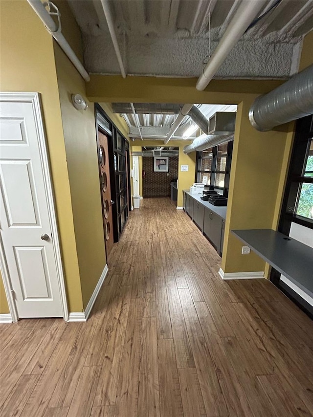 corridor with baseboards and wood finished floors